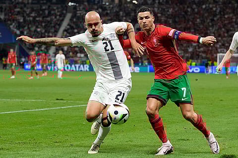 Cristiano Ronaldo and Vanja Drkusic battle for the ball